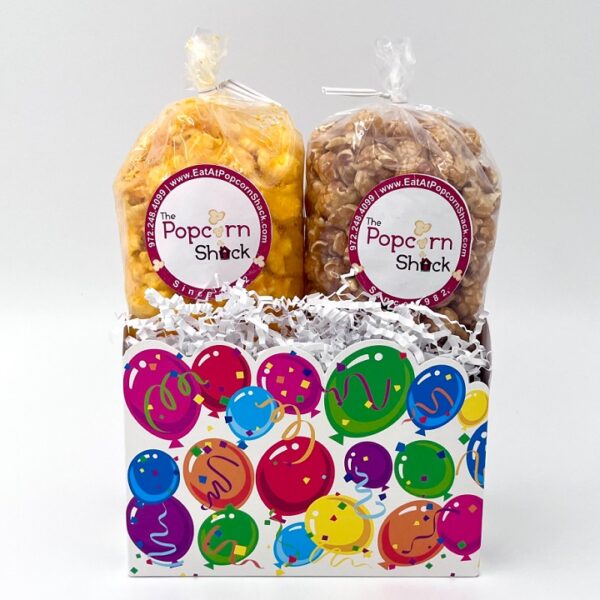 Two bags of popcorn in a white box decorated with multi-colored balloons.